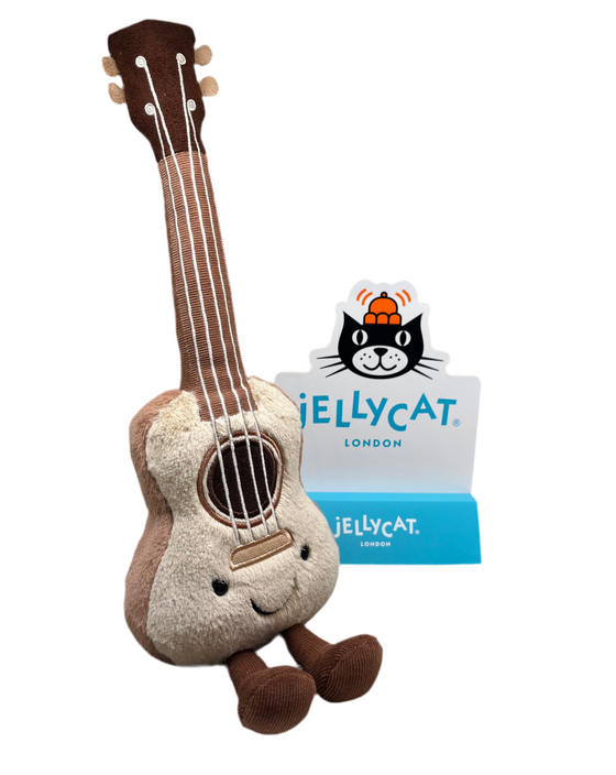 Beige fluffy ukulele with sewn on keys strings , smiley face and corduroy legs