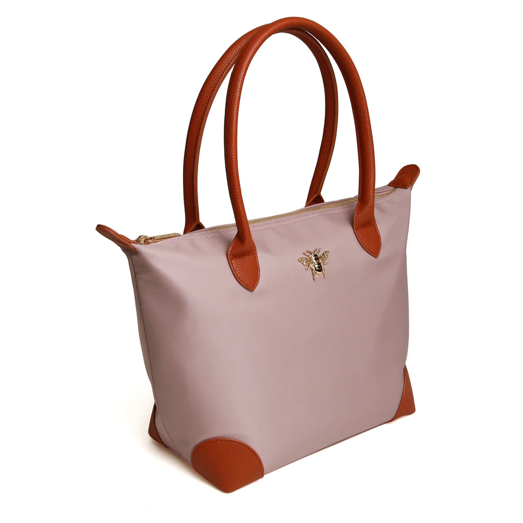 large pink tote bag with leather trimmings, a leather handle and a gold bee on the front