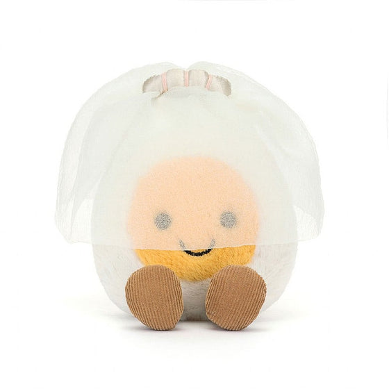 white boiled egg with a yellow smile,  wearing a veil and sat down with legs sticking out.