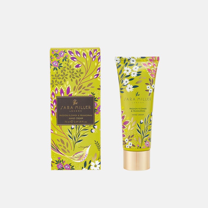 hand cream in a lime packaging with purple and pink flowers and birds with a gold cap