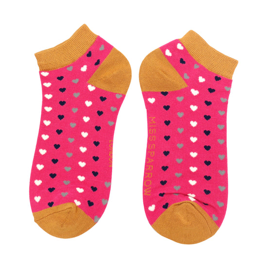 trainer socks with mustard ankle cuffs, toes and heels with a pattern of white, navy and silver hearts on a hot pink background