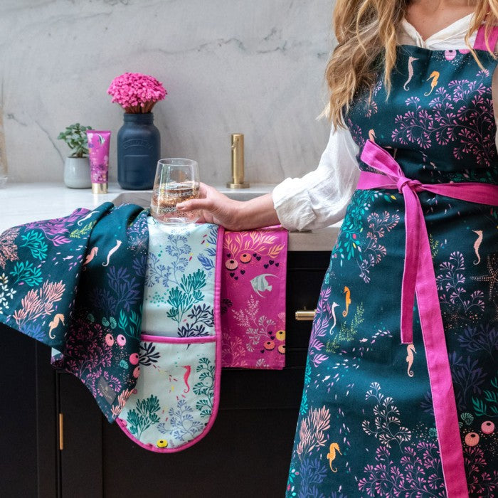 cotton sara miller apron with navy and deep purple green and pink under the water design with sea horses and a fushia strap